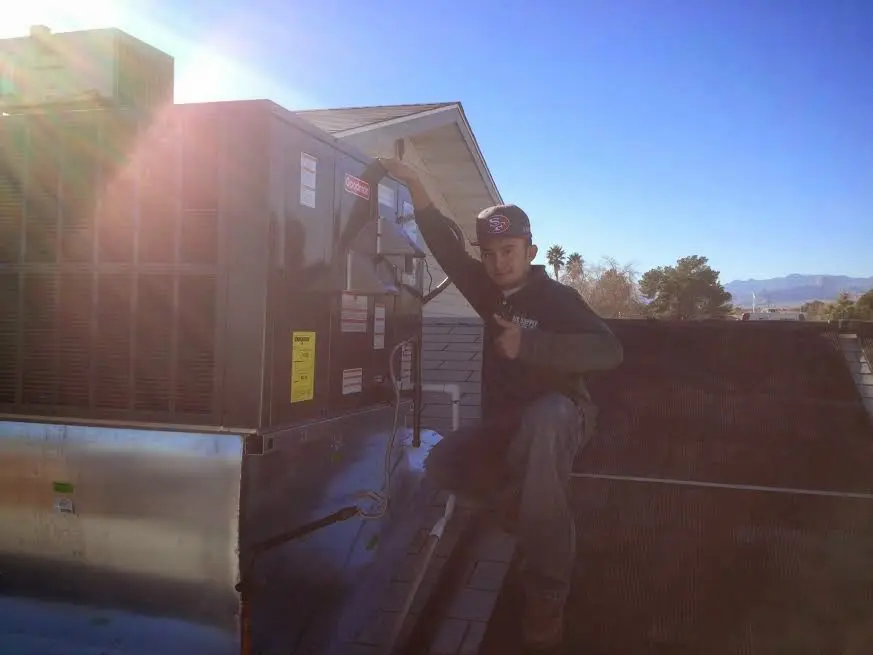 HVAC technician performing Heat Pump Repair on a rooftop unit in Albertville