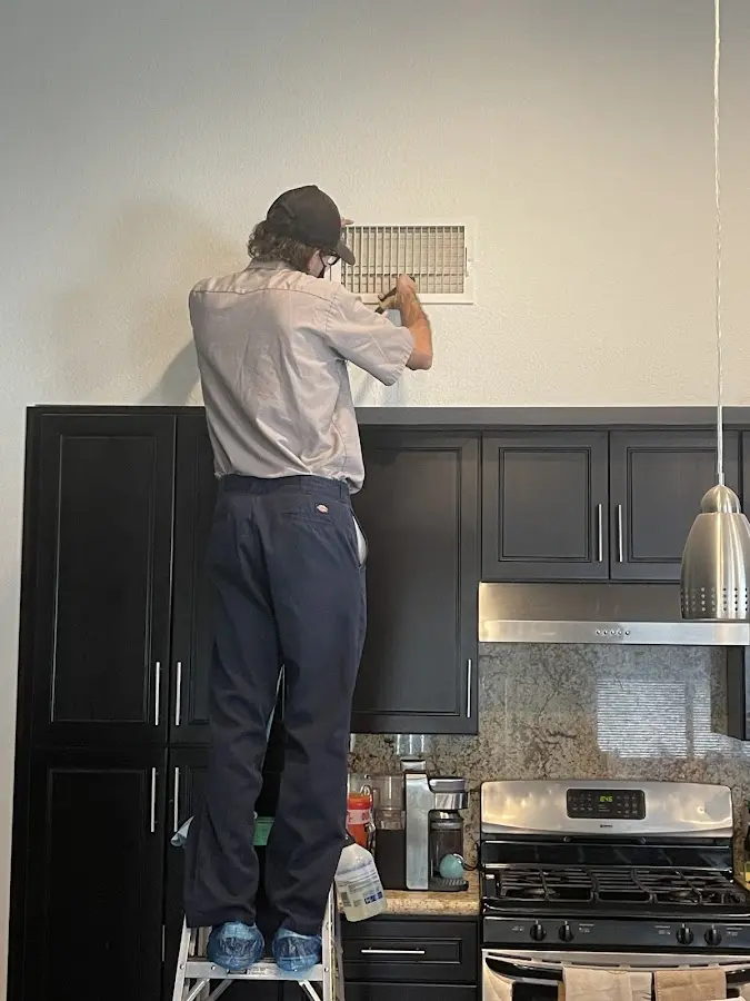 Technician inspecting an air vent during HVAC service in Albertville